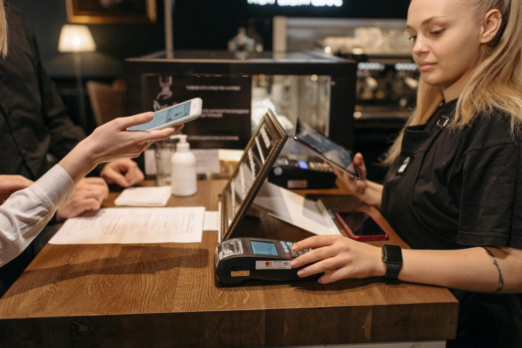 Customer using mobile phone Customer using mobile phone for contactless payment at a coffee shop counter with a barista.