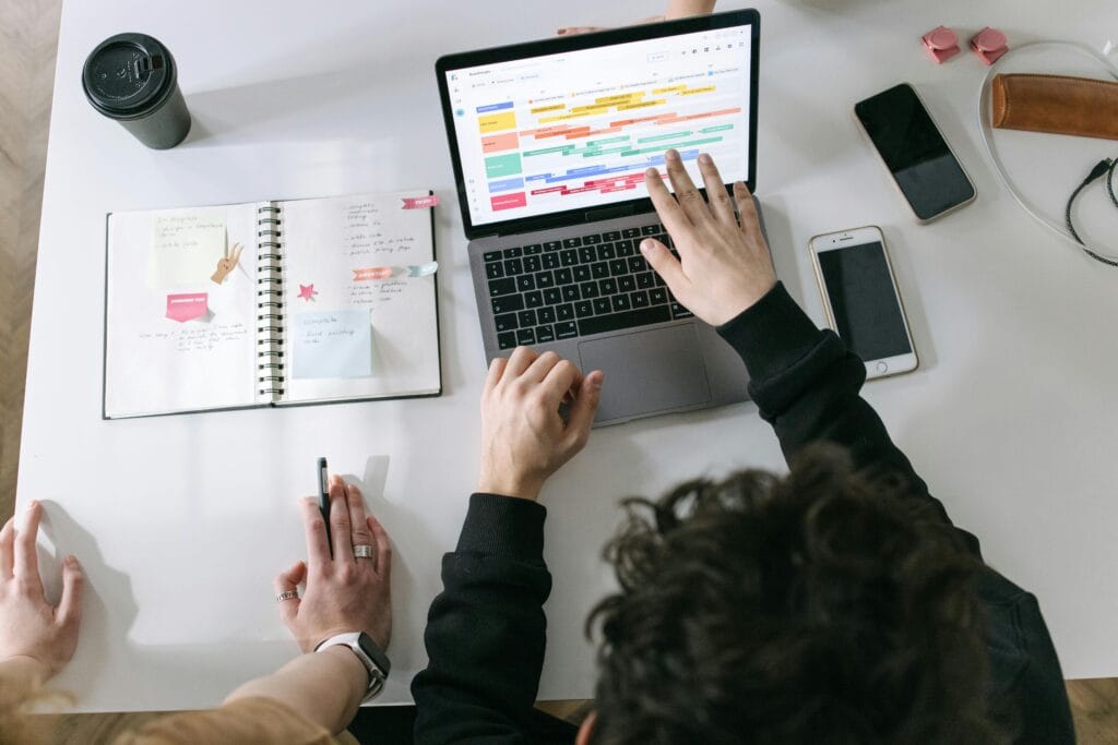 pexels-photo-7213549-7213549 Two people collaborating on a laptop and planner at a vibrant modern office desk.